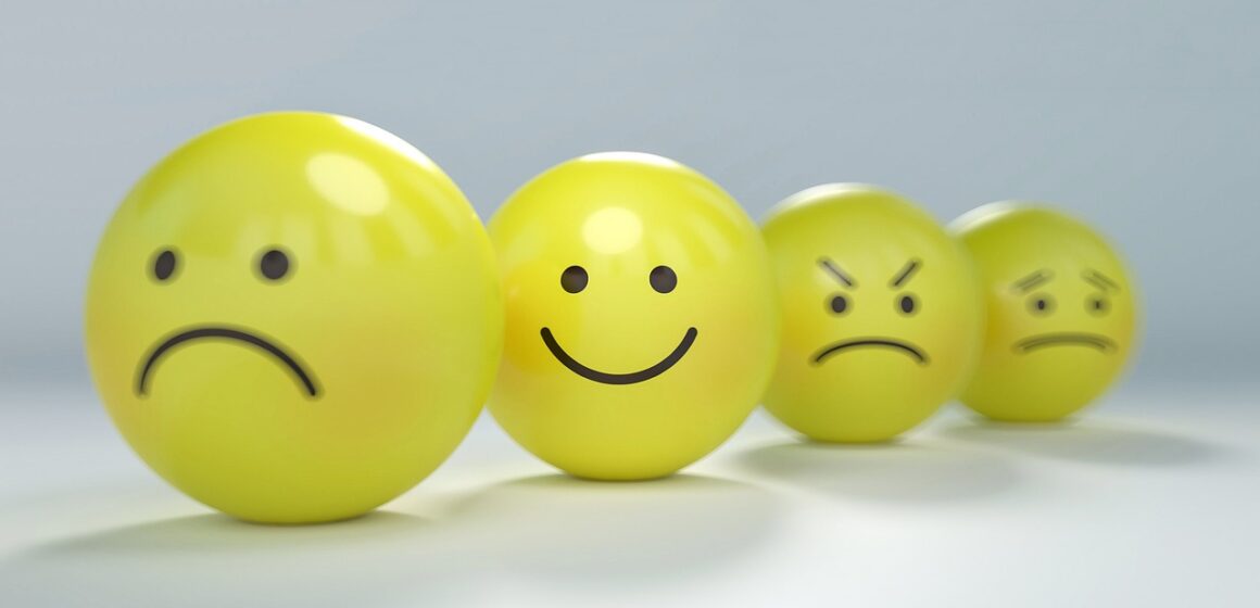 Cztery żółte kule na rozmytym tle. Każda z kul ma przedstawia inne emocje od smutku, uśmiechu, gniewu i żalu.