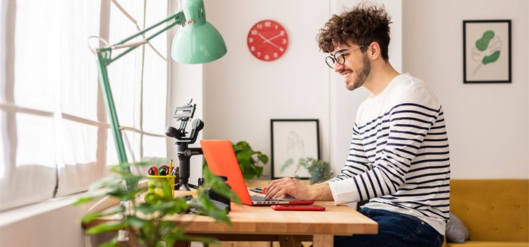Młody mężczyzna siedzi przy biurku i pracuje na komputerze.